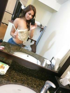 Sassy brunette stripping in front of the mirror and making selfies on fanspics.net