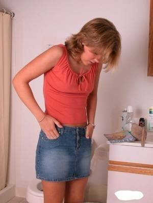 Amateur girl Karen hikes her denim skirt in the bathroom to expose her panties on fanspics.net
