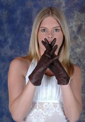 Blonde female pulls on brown leather gloves while wearing a white dress on fanspics.net