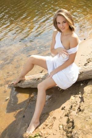 White teen of legal age shows off her naked body on a log that's beached on fanspics.net