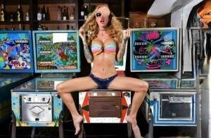 Inked chick Sarah Jessie toys her pussy atop a pinball machine while alone on fanspics.net