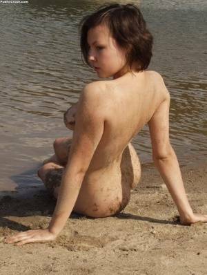 Amateur girl covers her naked body in sand while at a nude beach on fanspics.net