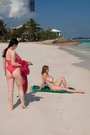 Busty lesbian girls let their huge knockers loose to kiss & lick on the beach on fanspics.net