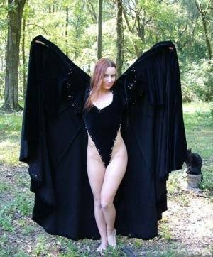 Redhead amateur Amber Lily models nude in a forest draped in a black cape on fanspics.net