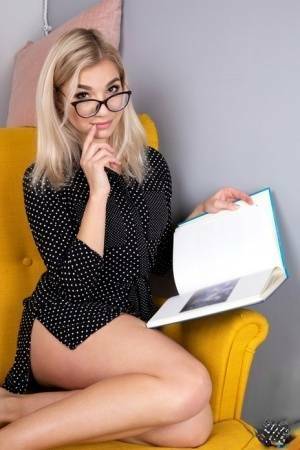 Geeky blonde Amelia undresses on a chair before playing with her shaved pussy on fanspics.net