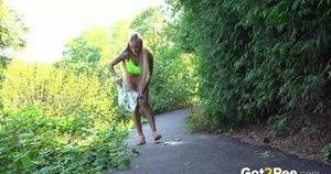 Blonde teen Daisy Lee takes a piss on a paved path through the woods on fanspics.net