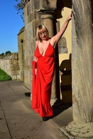 Older blonde Barby Slut doffs a red evening gown to pose nude in hosiery on fanspics.net