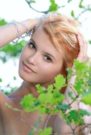 Adorable redhead Violla A displays her naked teen body atop a rock outdoors on fanspics.net